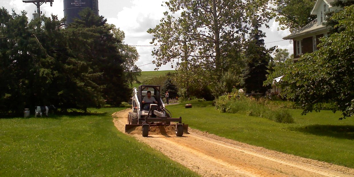 Equipment preparing a residential driveway for asphalt paving